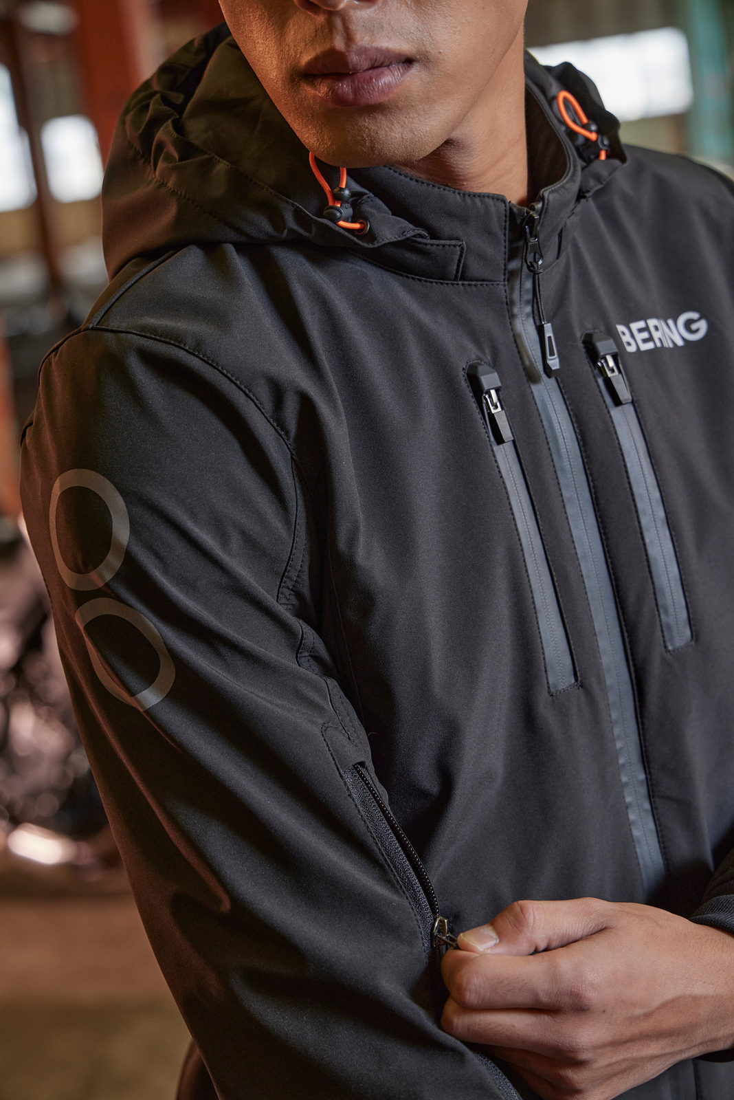 Portrait en veste &agrave; capuche, cordon orange, logo Bering.