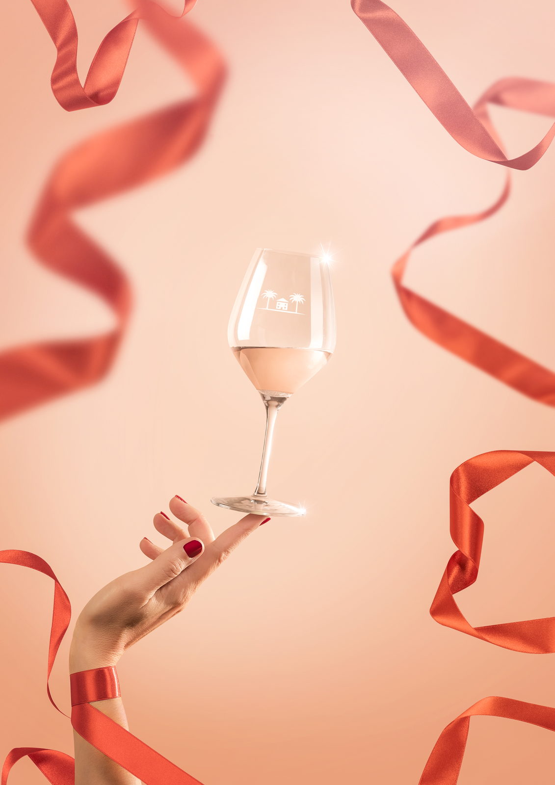 Verre de ros&eacute; et rubans rouges sur fond corail.